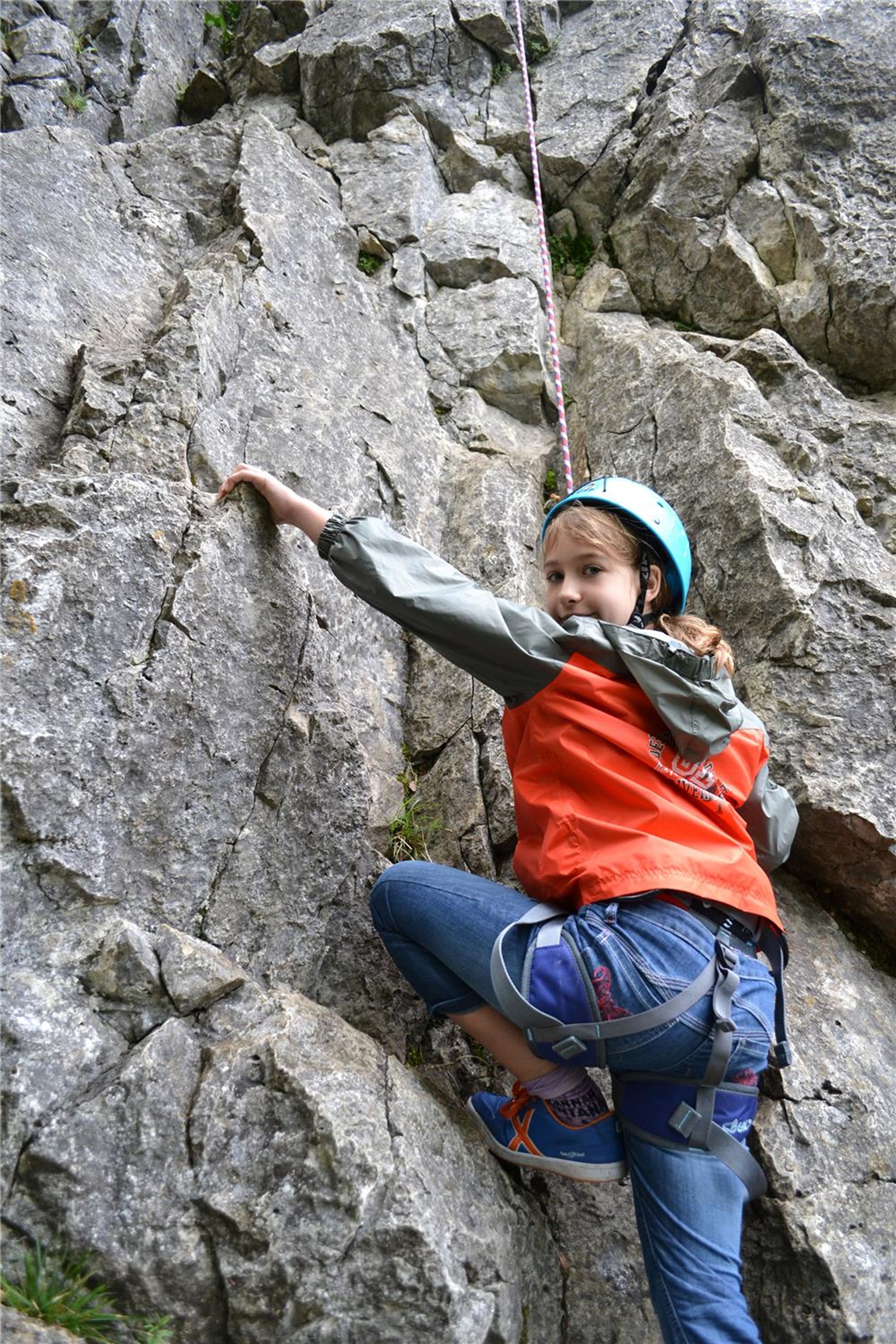 ein Mädchen klettert an einem Seit eine Steilwand hinauf